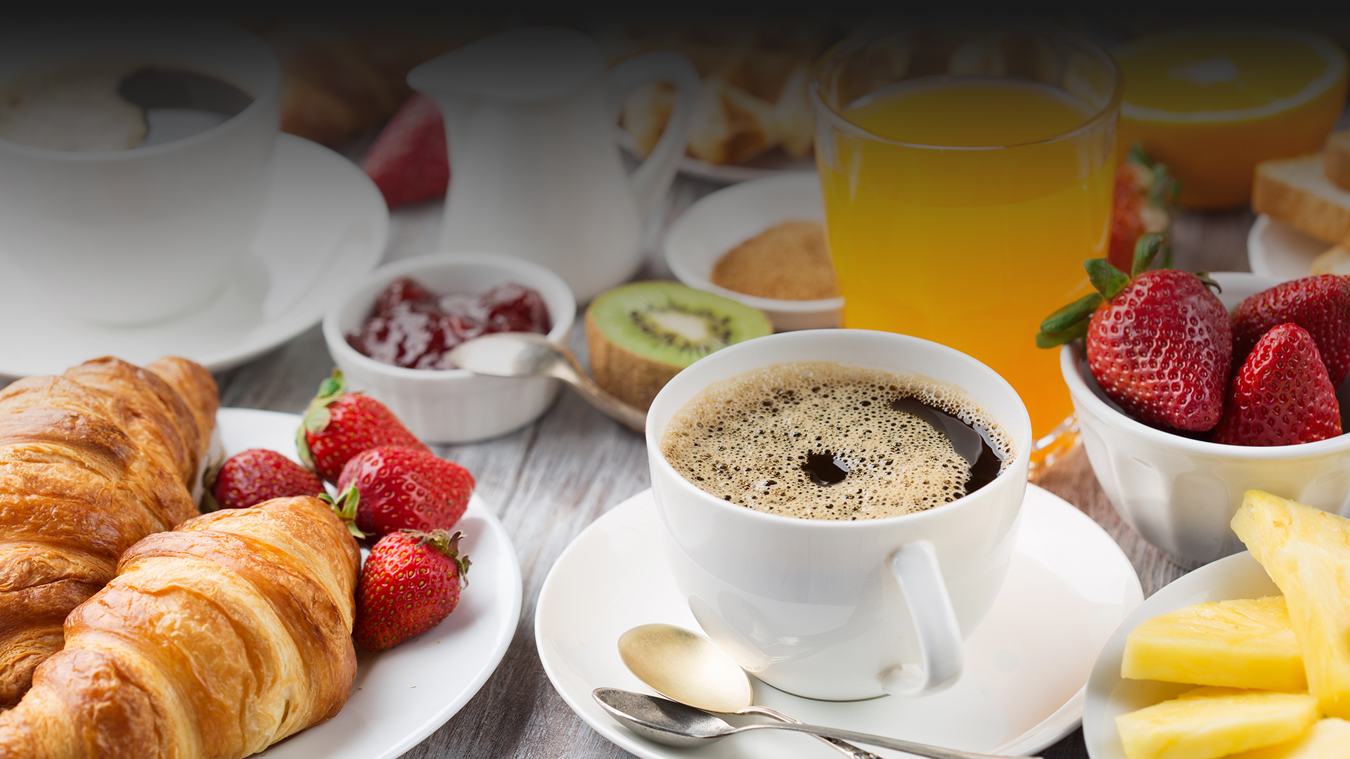 Coffee served with fresh fruit sides and baked goods at Egg Haven Pancakes & Cafe.