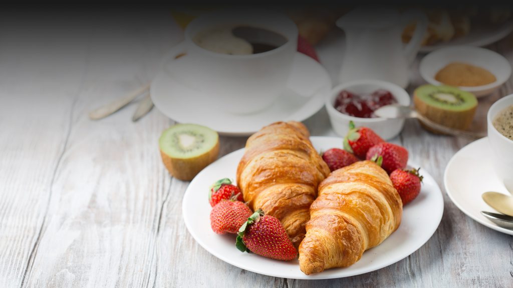 Breakfast spread of croissants, fruit and coffee